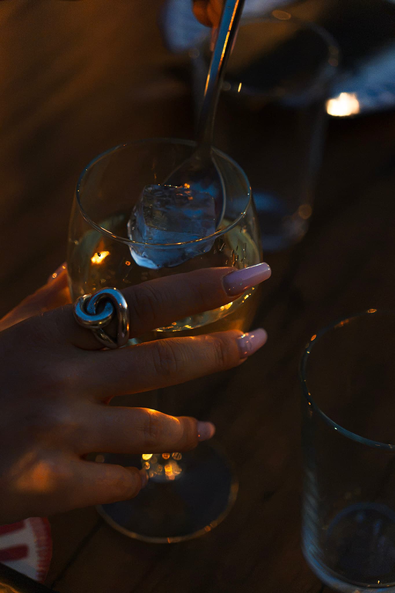 Un verre de vin blanc avec un glaçon, à la lueur des bougies